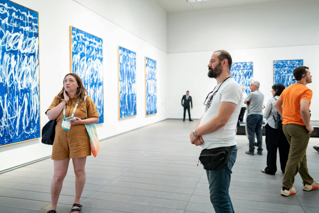 People viewing large-scale blue abstract paintings in a contemporary gallery space