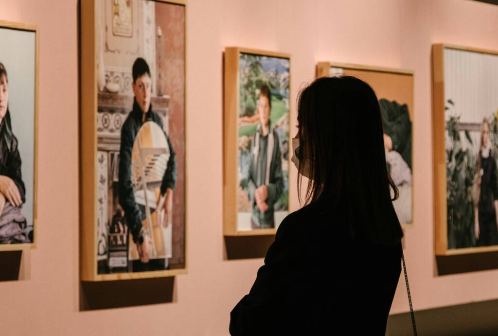Visitor viewing framed portrait photographs in a gallery, suggesting the critical looking and exhibition context of Central Saint Martins BA Fine Art.
