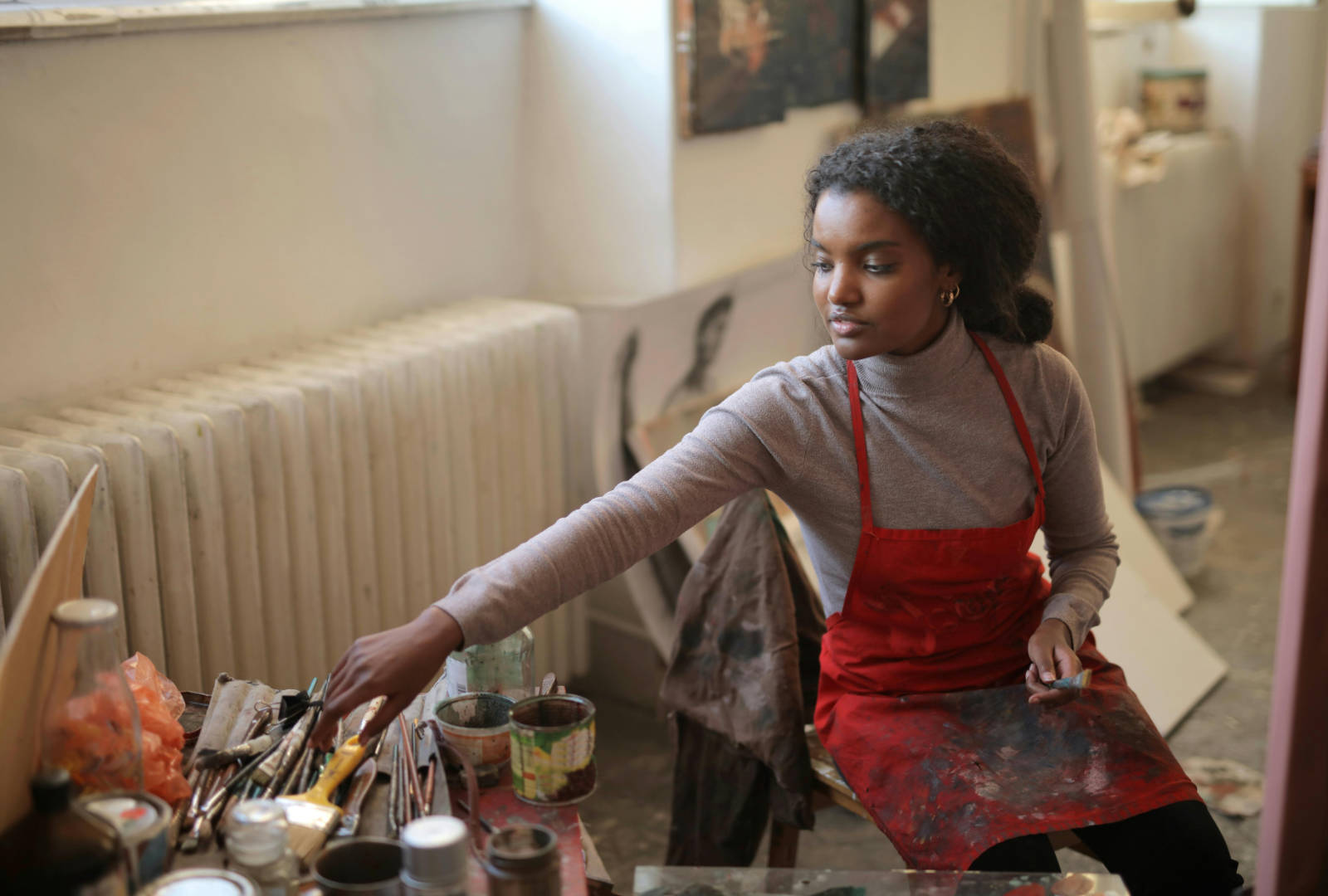 Artist in a studio reaching for brushes, illustrating the studio practice behind Oxford Ruskin MFA portfolio requirements.