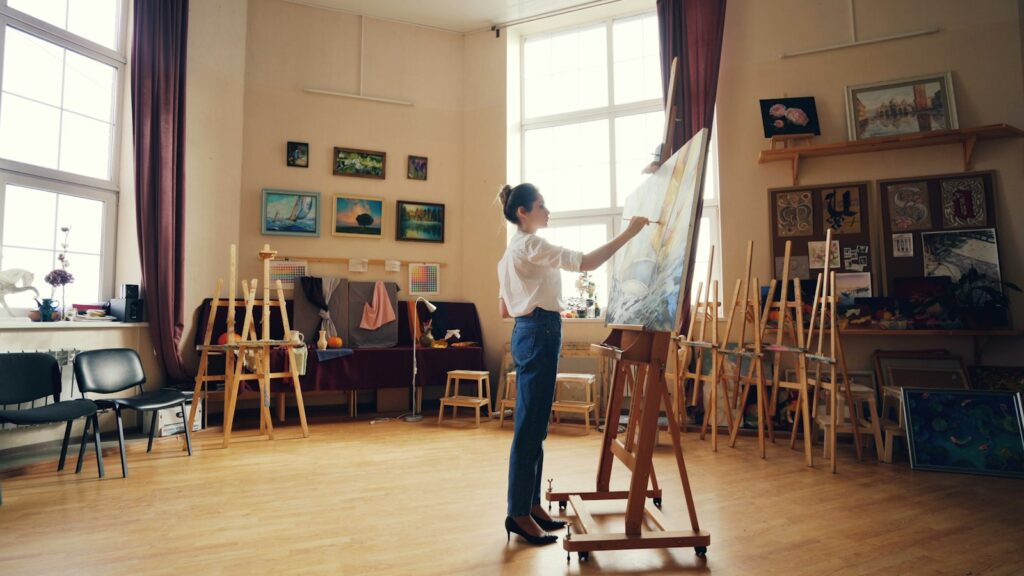Artist painting at an easel in a bright studio, for applicants meeting the Slade School of Fine Art BA/BFA Fine Art portfolio requirements