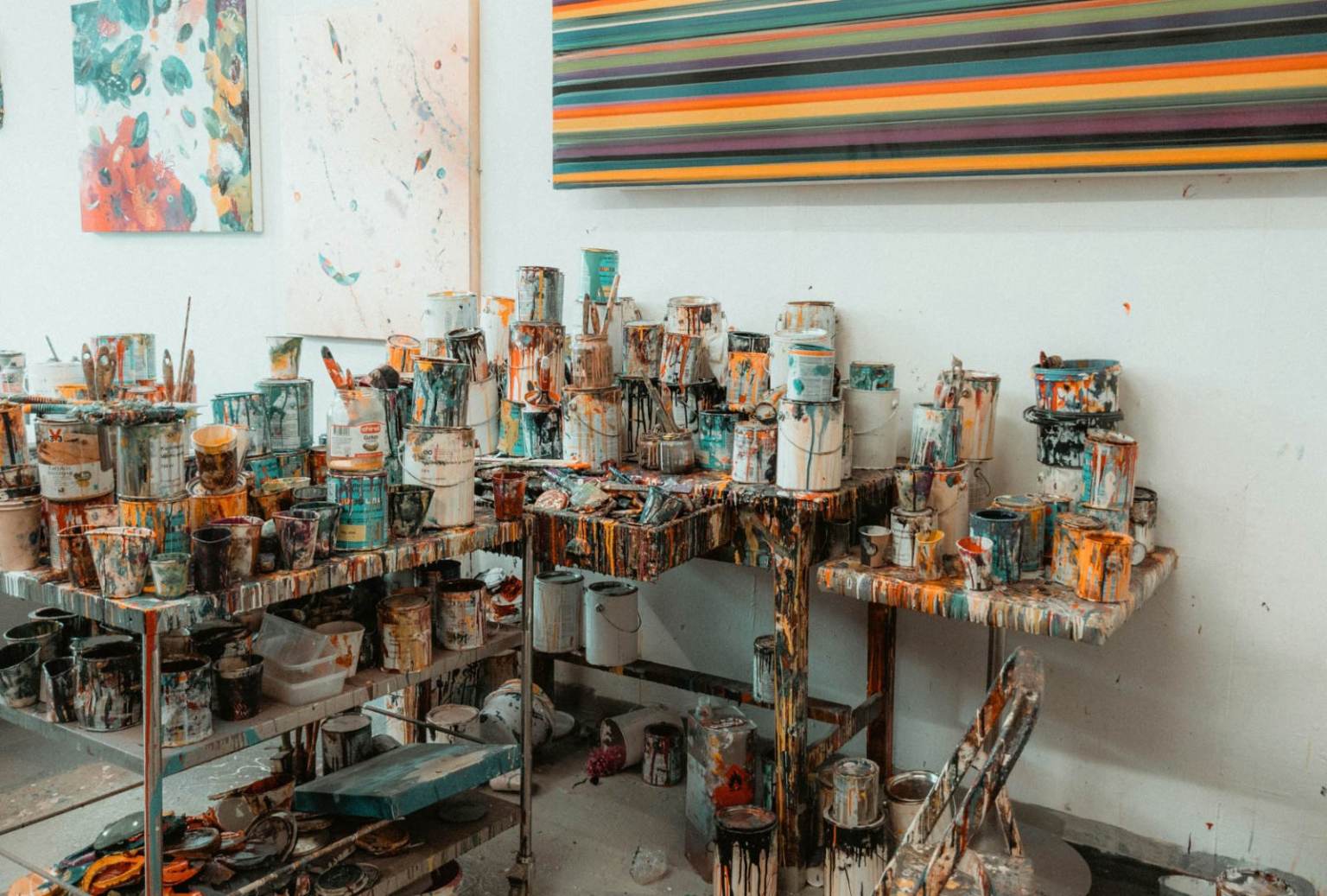 Paint-splattered studio tables with tins, brushes and abstract paintings, suggesting the material research behind an Edinburgh College of Art BA Fine Art portfolio.