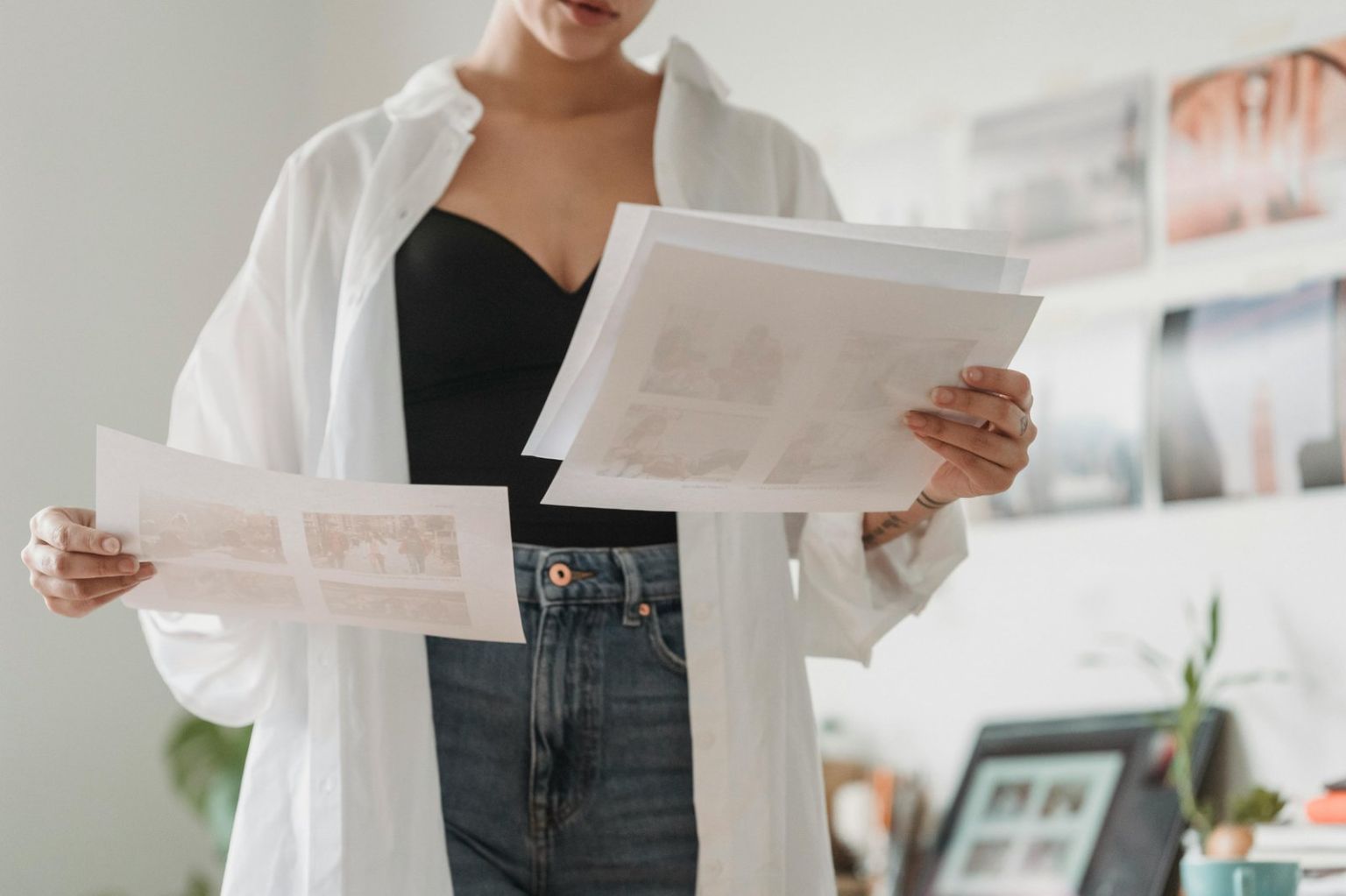 Art student reviewing printed fine art portfolio pages in a bright studio space