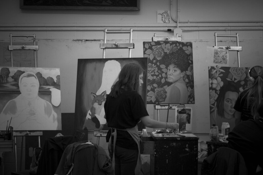 Painter among portrait paintings in a studio, for applicants meeting the MICA BFA Painting portfolio requirements