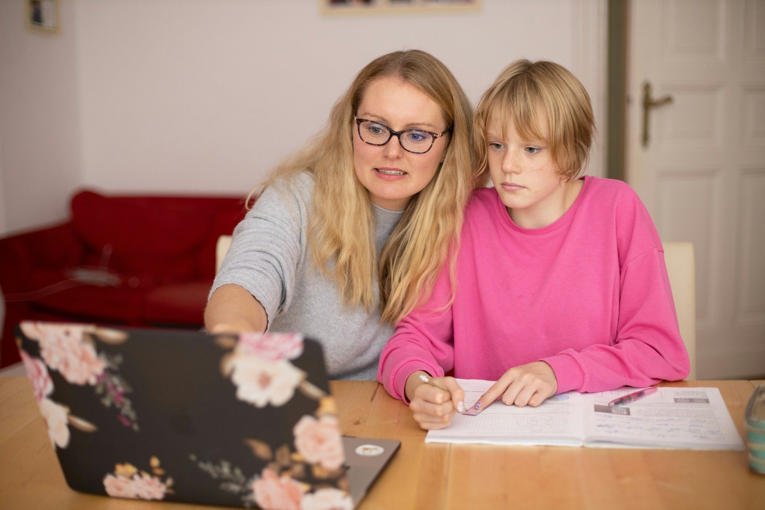 A parent and teenager at a table with a laptop and notebook, working through art school applications together