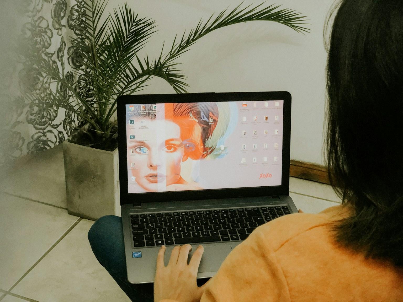 A student at a laptop looking at a painted portrait on screen during an online session