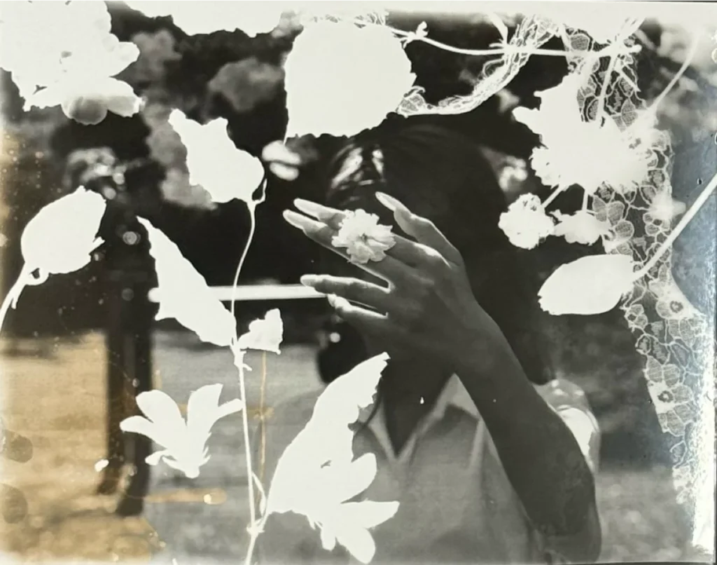 Black and white photograph of a raised hand surrounded by white flower shapes
