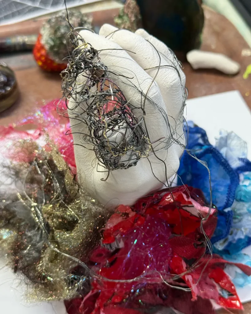 Plaster hand wrapped in black wire with textile flowers